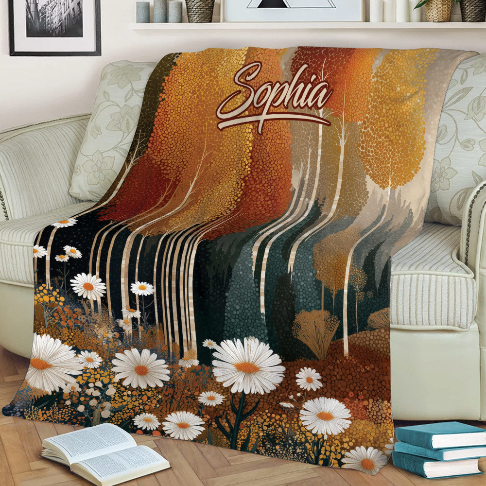 Close view of an autumn woodland throw blanket with colorful trees and white flowers