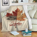 Custom autumn leaves throw blanket displayed on a cozy sofa with books and home decor