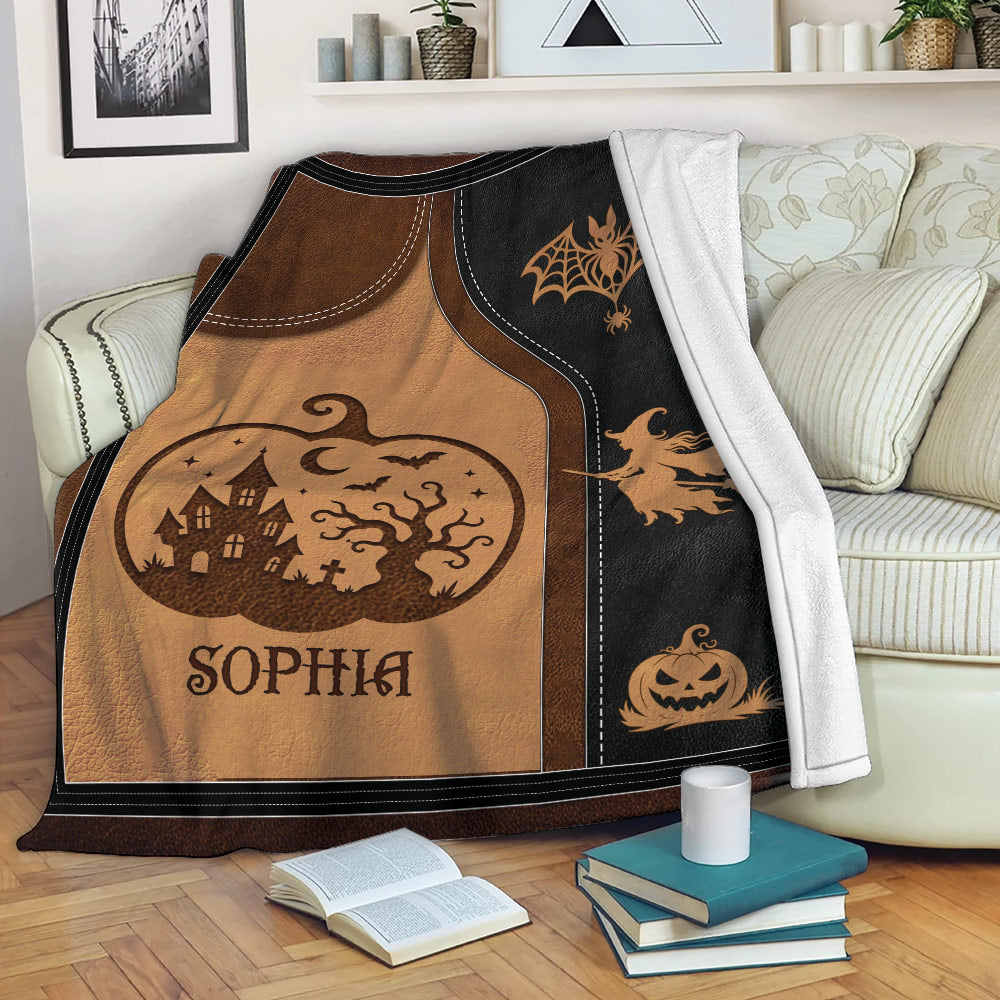 Halloween throw blanket draped over a sofa with witch, pumpkin, haunted house, and spiderweb artwork