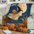 Close view of Halloween blanket artwork showing a smiling ghost witch, broom, pumpkins, and autumn grasses