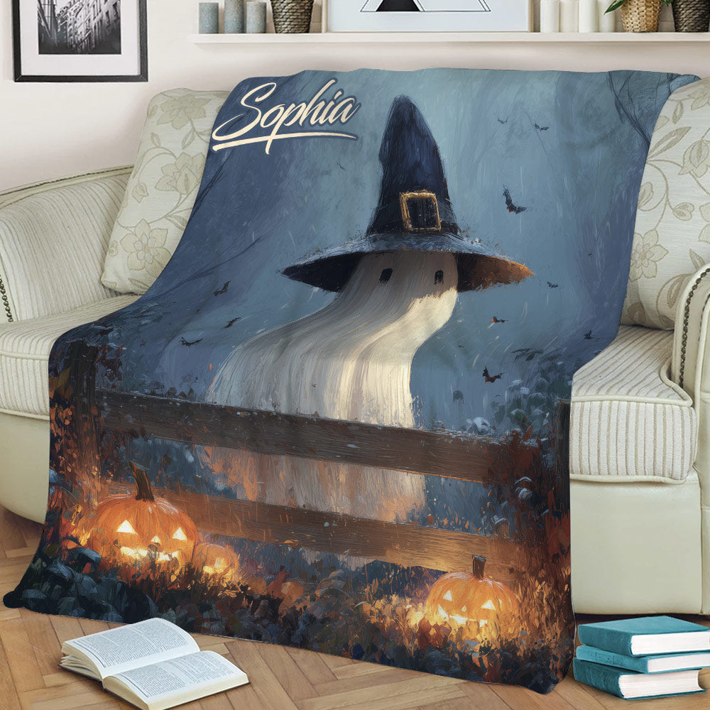 Close lifestyle view of a Halloween blanket with ghost, witch hat, bats, and pumpkin artwork on a sofa