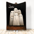 Halloween throw blanket featuring six soft white ghosts on a black and brown background