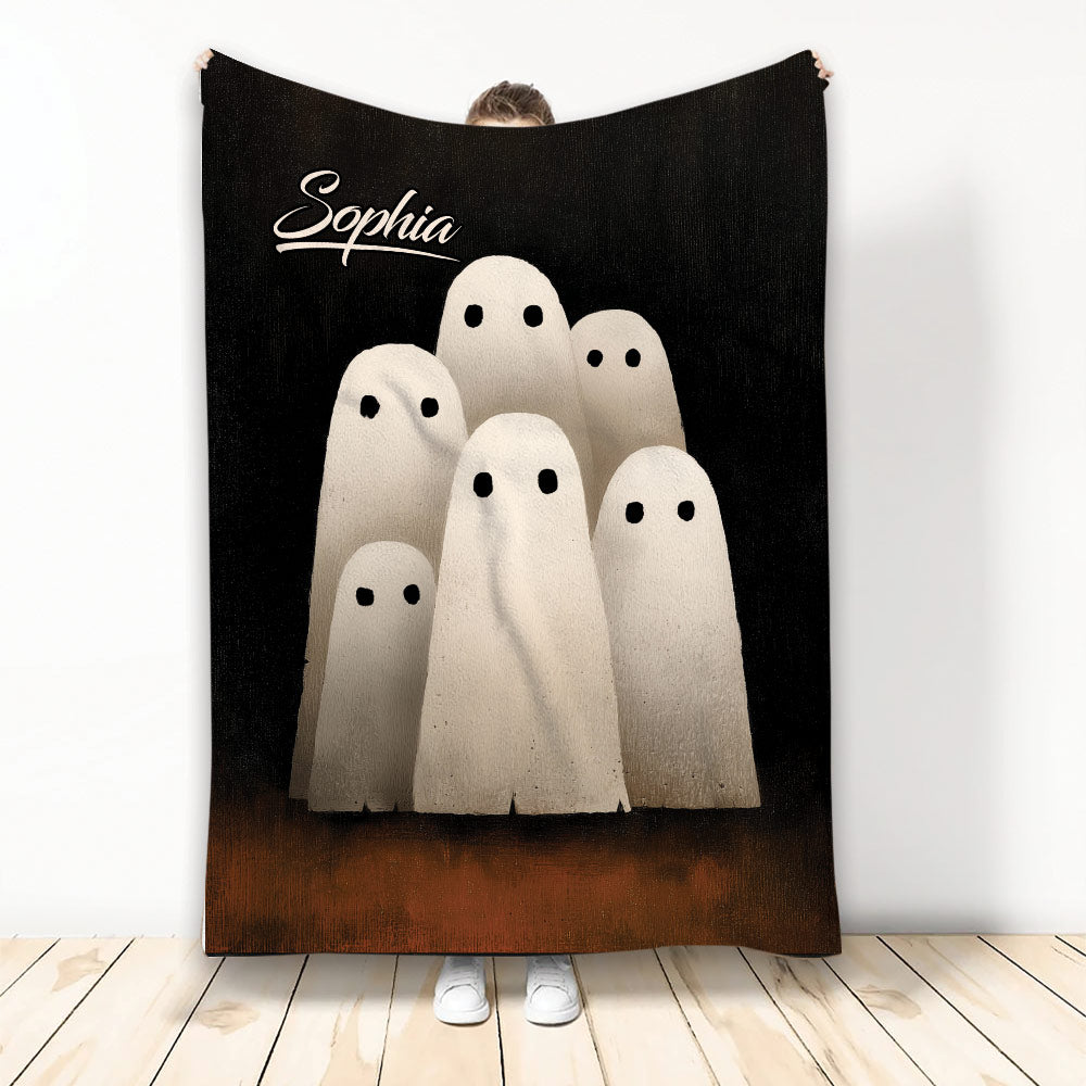 Halloween throw blanket featuring six soft white ghosts on a black and brown background