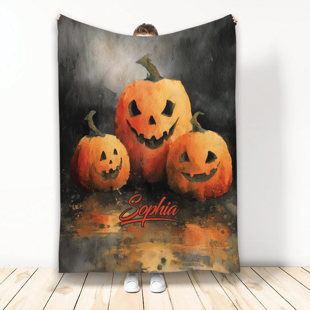 Halloween blanket featuring three glowing jack-o'-lantern pumpkins in moody orange and black artwork