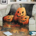 Close view of a Halloween throw blanket with smiling jack-o'-lantern artwork on a sofa