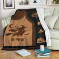 Halloween throw blanket draped over a sofa with witch, bat, cauldron, and jack-o'-lantern designs