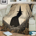 Close view of a Halloween blanket featuring a witch silhouette, trees, and botanical details