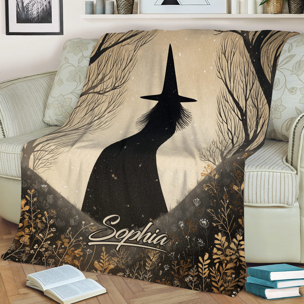 Close view of a Halloween blanket featuring a witch silhouette, trees, and botanical details