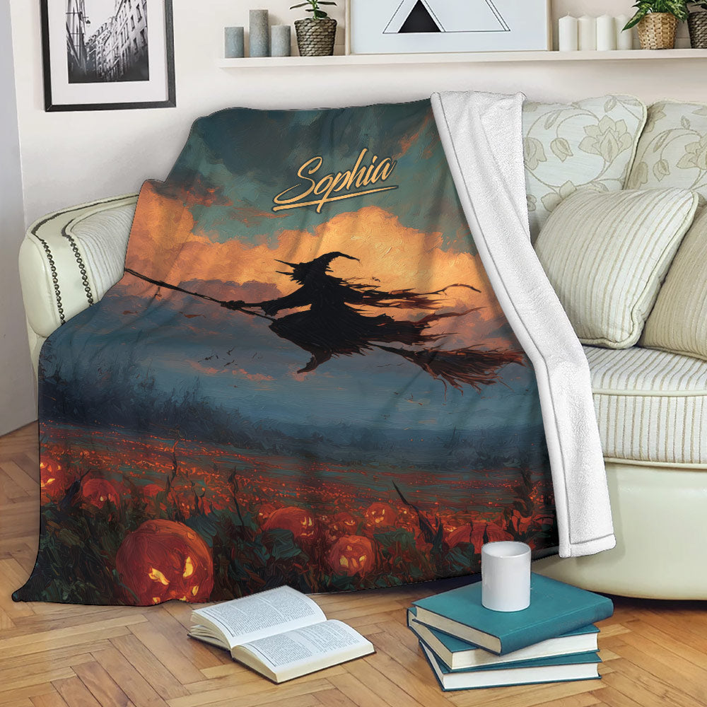 Halloween throw blanket draped over a sofa with witch artwork, glowing jack-o-lanterns, and dark fall colors