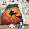 Halloween witch throw blanket displayed on a couch with bats, moonlit artwork, and warm orange tones
