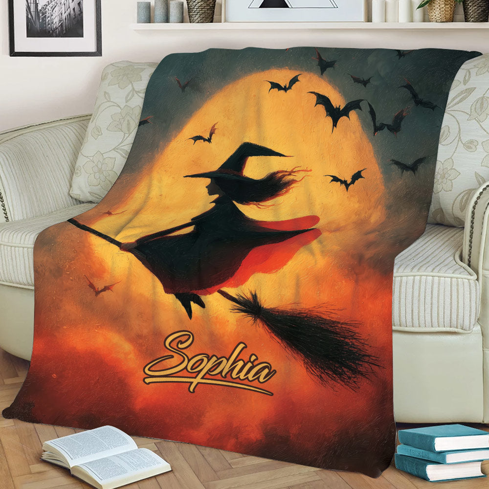 Spooky witch throw blanket draped over a sofa with bats, broomstick, and glowing Halloween moon