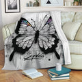 Intricate butterfly throw blanket draped over a sofa with black, white, purple, blue, and pink wing details