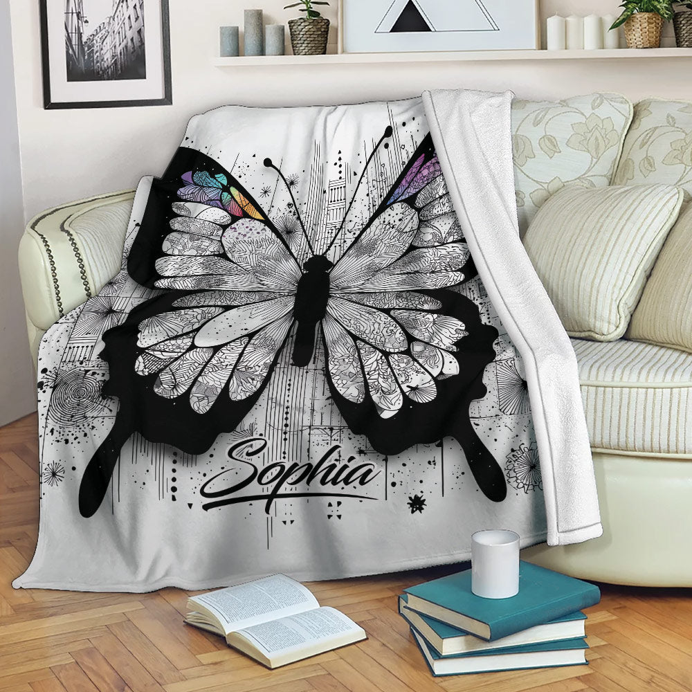 Intricate butterfly throw blanket draped over a sofa with black, white, purple, blue, and pink wing details