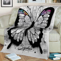 Large artistic butterfly blanket displayed on a sofa, featuring detailed wings and abstract black-and-white artwork