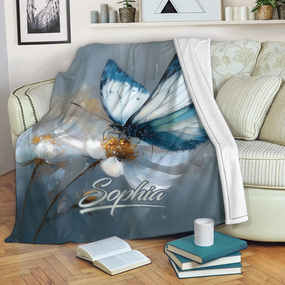 Blue butterfly and floral throw blanket draped over a cozy sofa with books and a cup