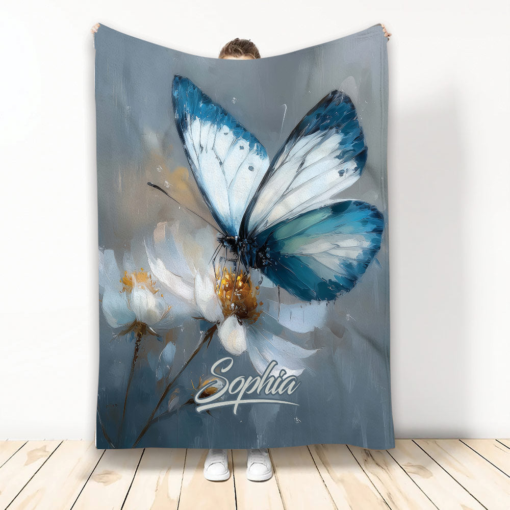 Blue butterfly blanket with white flowers displayed against a wall in a full-length product view