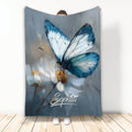 Blue butterfly blanket with white flowers displayed against a wall in a full-length product view