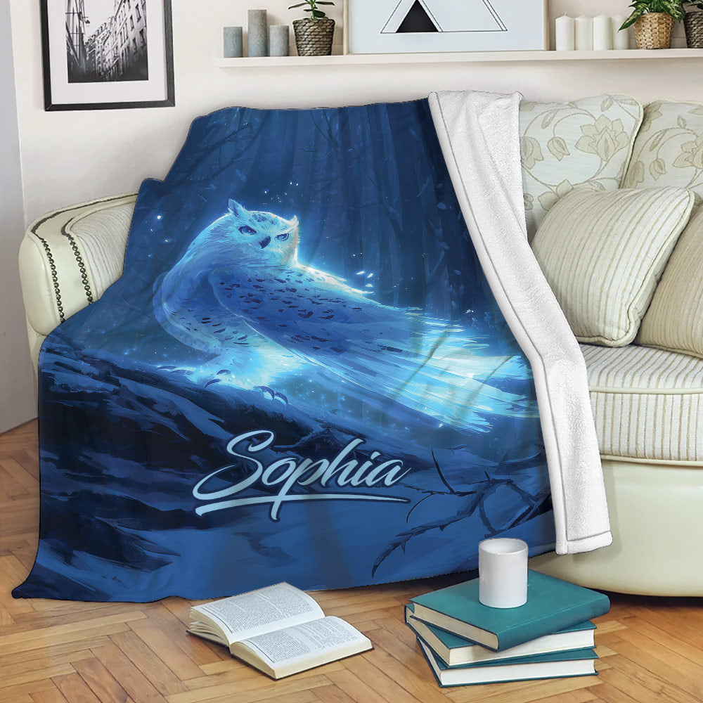 Blue owl throw blanket draped over a sofa with glowing forest artwork