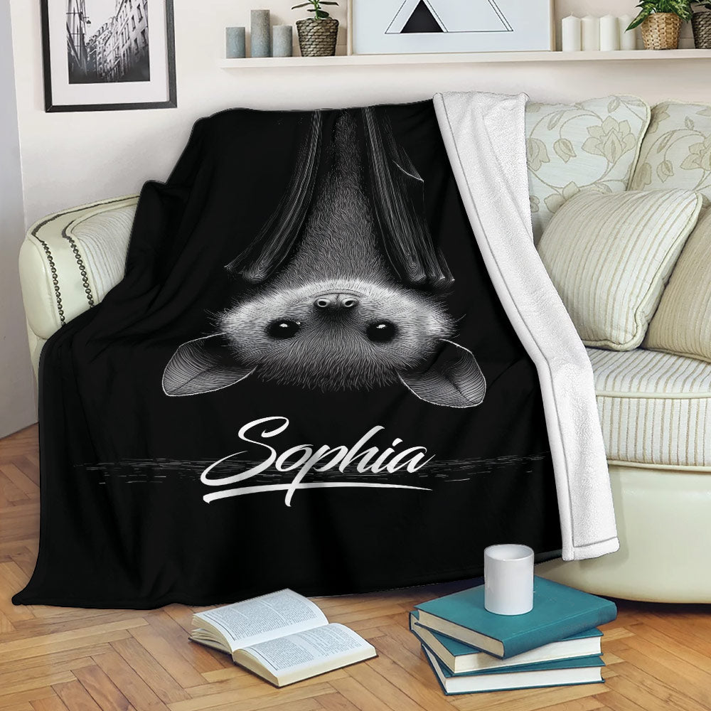 Black bat blanket draped over a sofa with an upside-down bat illustration