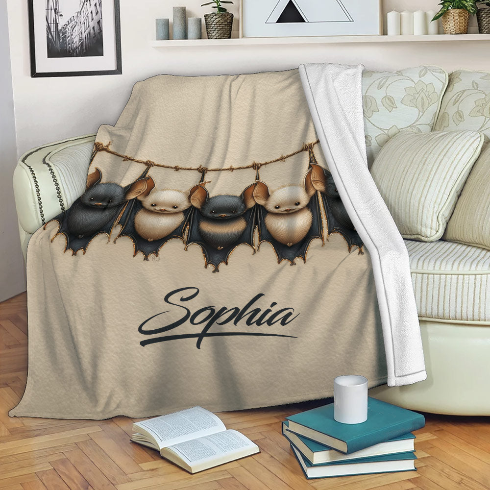 Bat throw blanket displayed on a sofa with five hanging bats and cozy living room decor