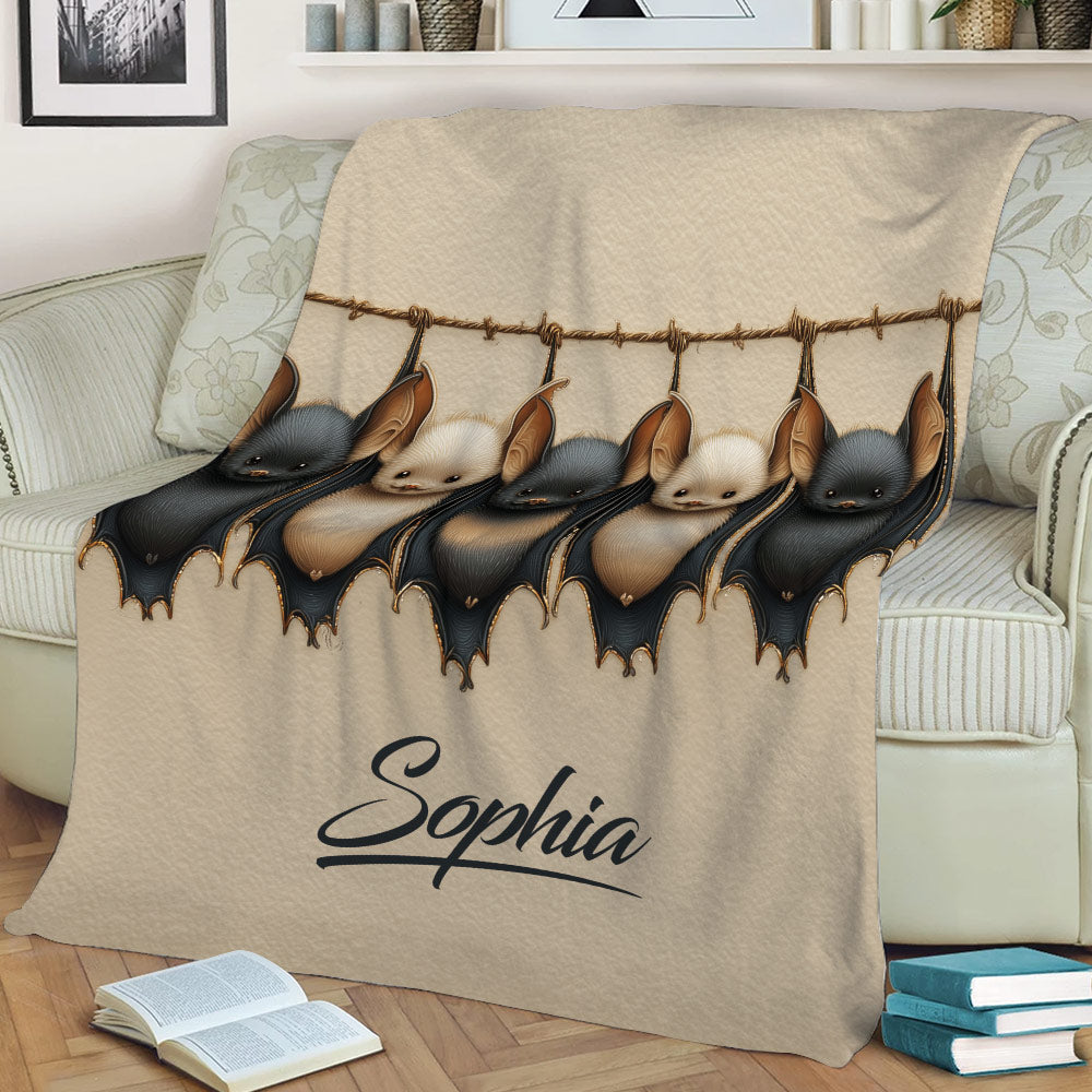 Close lifestyle view of a bat blanket with detailed black and tan bats draped over a sofa