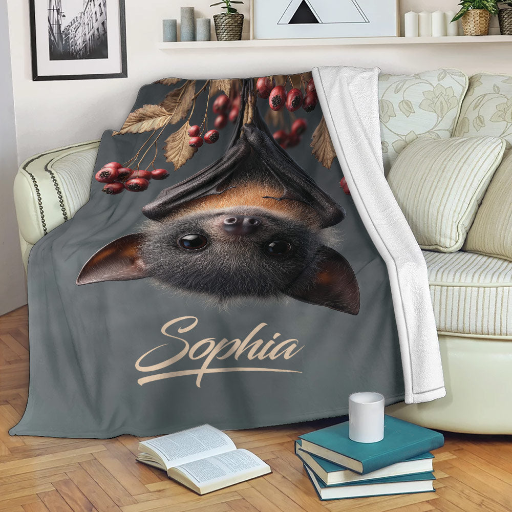 Bat throw blanket displayed on a sofa with woodland foliage and autumn berry artwork
