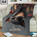 Close view of bat artwork on a throw blanket with dark tones, leaves, and red berries