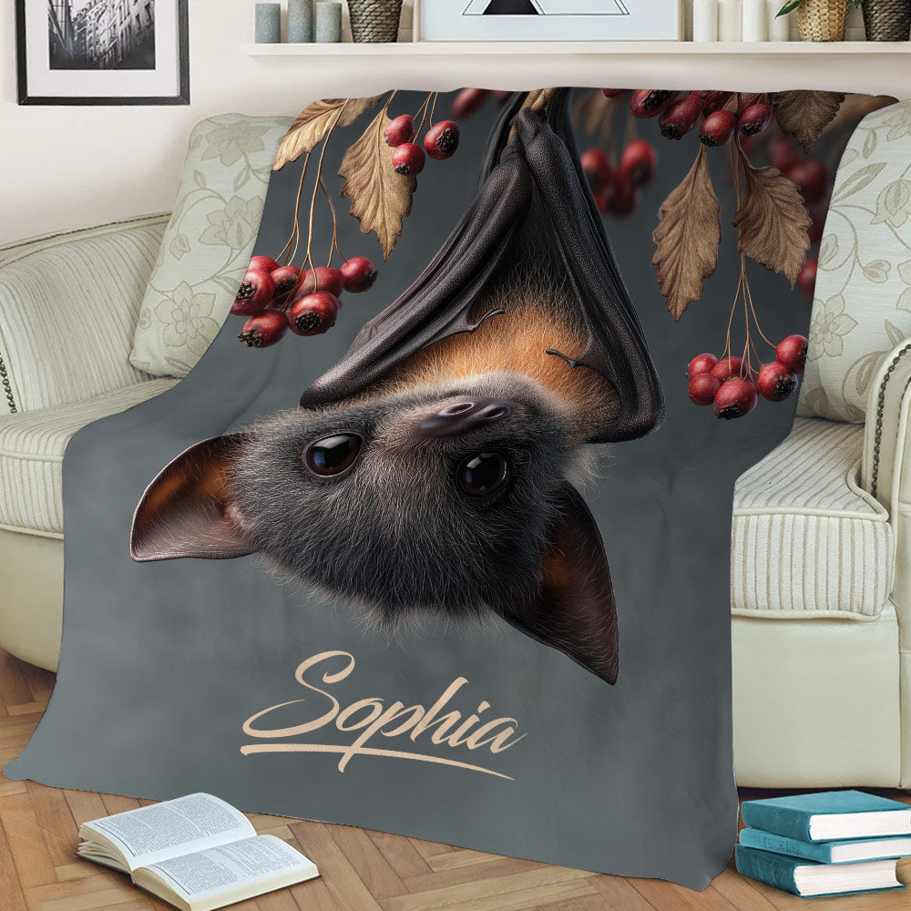 Close view of bat artwork on a throw blanket with dark tones, leaves, and red berries