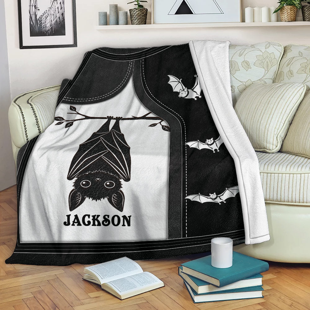 Black and white bat throw blanket draped over a sofa with hanging bat artwork and smaller flying bats