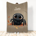 Cute black spider throw blanket with large expressive eyes, autumn leaves, and warm neutral artwork