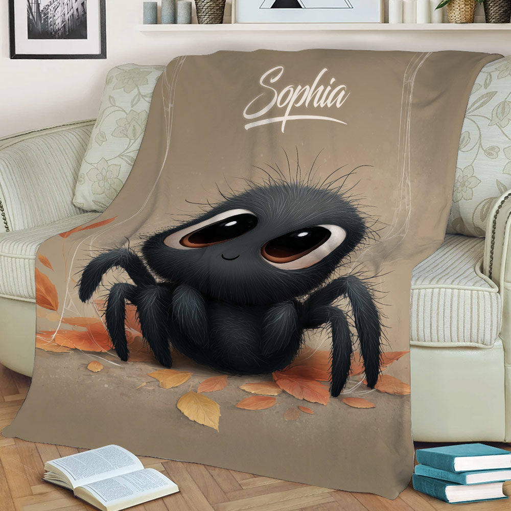 Close view of a cute black spider throw blanket displayed on a sofa with autumn leaf artwork