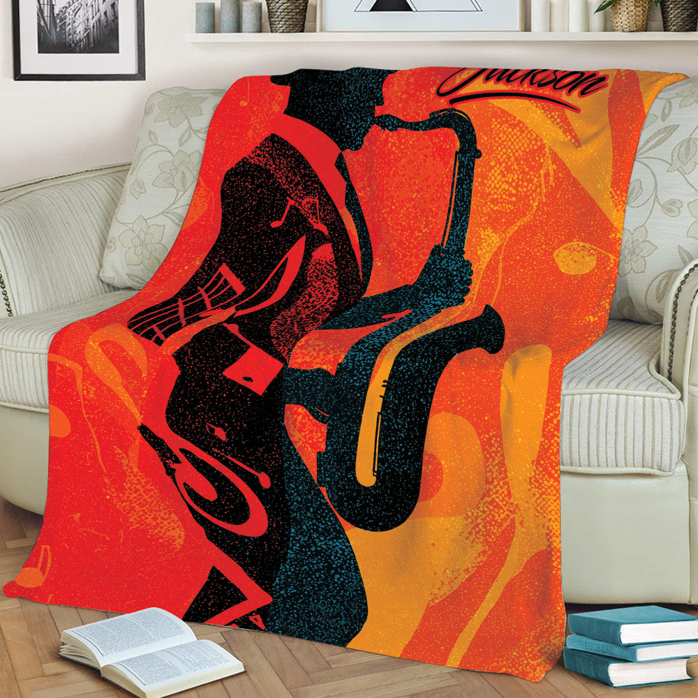 Saxophone throw blanket displayed on a couch with dramatic black musician artwork and a fiery abstract background