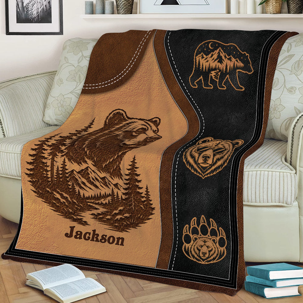 Rustic wildlife blanket draped over a sofa, featuring a bear, mountains, trees, and paw print designs