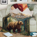 Rustic bear throw blanket displayed on a sofa with mountain scenery and evergreen forest artwork
