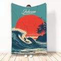 Surfing blanket with a silhouetted surfer riding a wave beneath a bold sunset and palm tree artwork