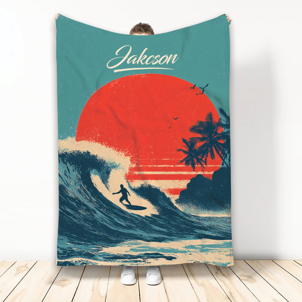 Surfing blanket with a silhouetted surfer riding a wave beneath a bold sunset and palm tree artwork