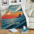 Surfing blanket draped over a sofa, featuring a retro sunset wave and surfer design