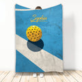 Blue pickleball throw blanket displayed with a yellow perforated ball and bold geometric court-inspired artwork