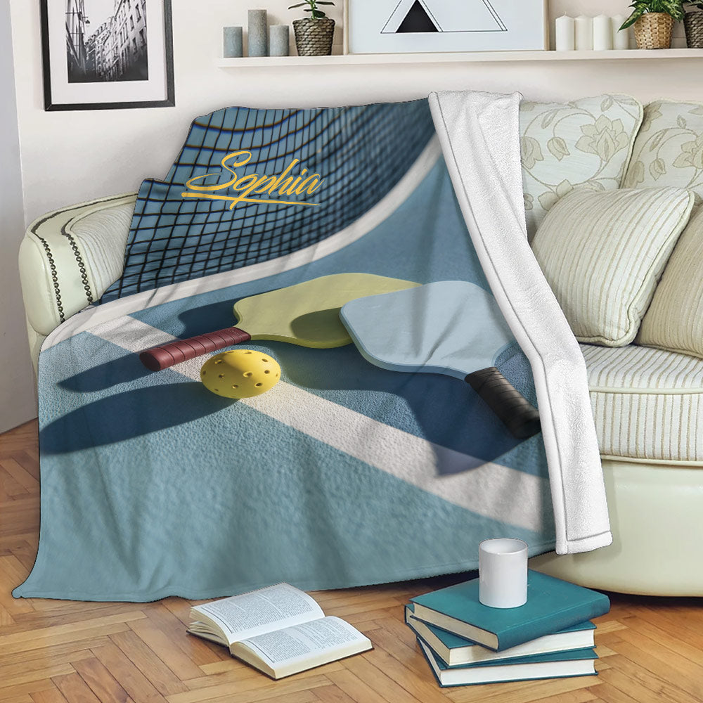 Pickleball throw blanket draped over a sofa with paddle and ball court design