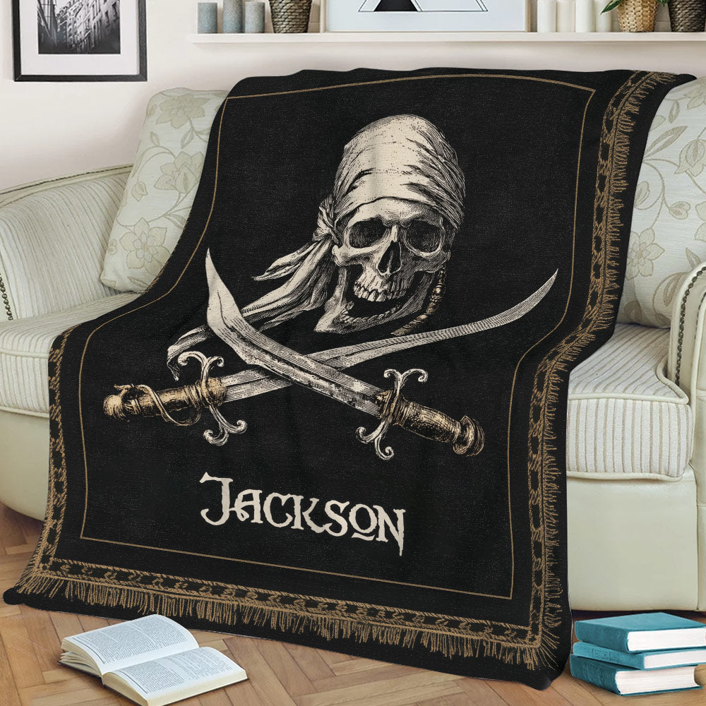 Black pirate throw blanket with skull artwork and ornate gold border on a couch