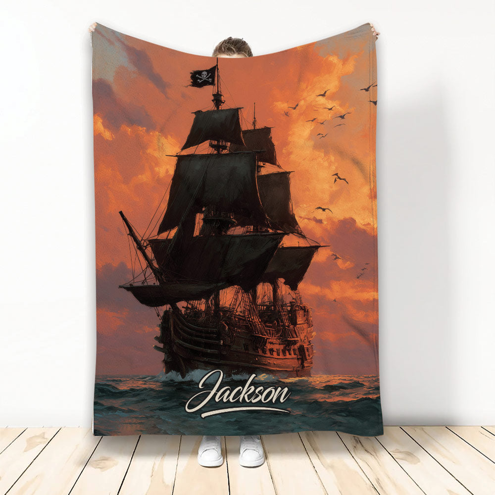 Pirate ship throw blanket with black sails, pirate flag, ocean waves, and dramatic orange sunset artwork
