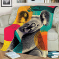 Close view of a colorful koala throw blanket styled across a sofa with books nearby