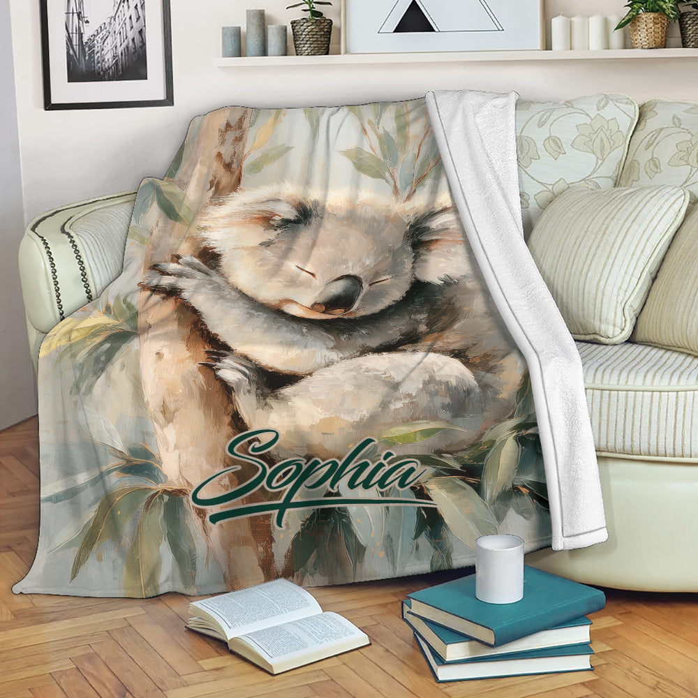 Koala throw blanket draped over a sofa with sleeping koala artwork and eucalyptus foliage