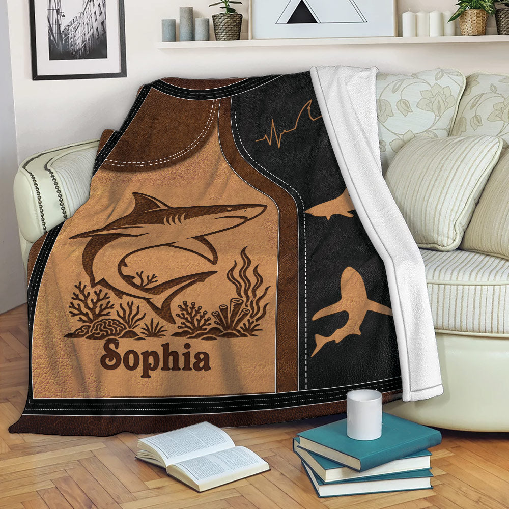 Shark throw blanket draped over a sofa with ocean-inspired artwork and multiple shark silhouettes
