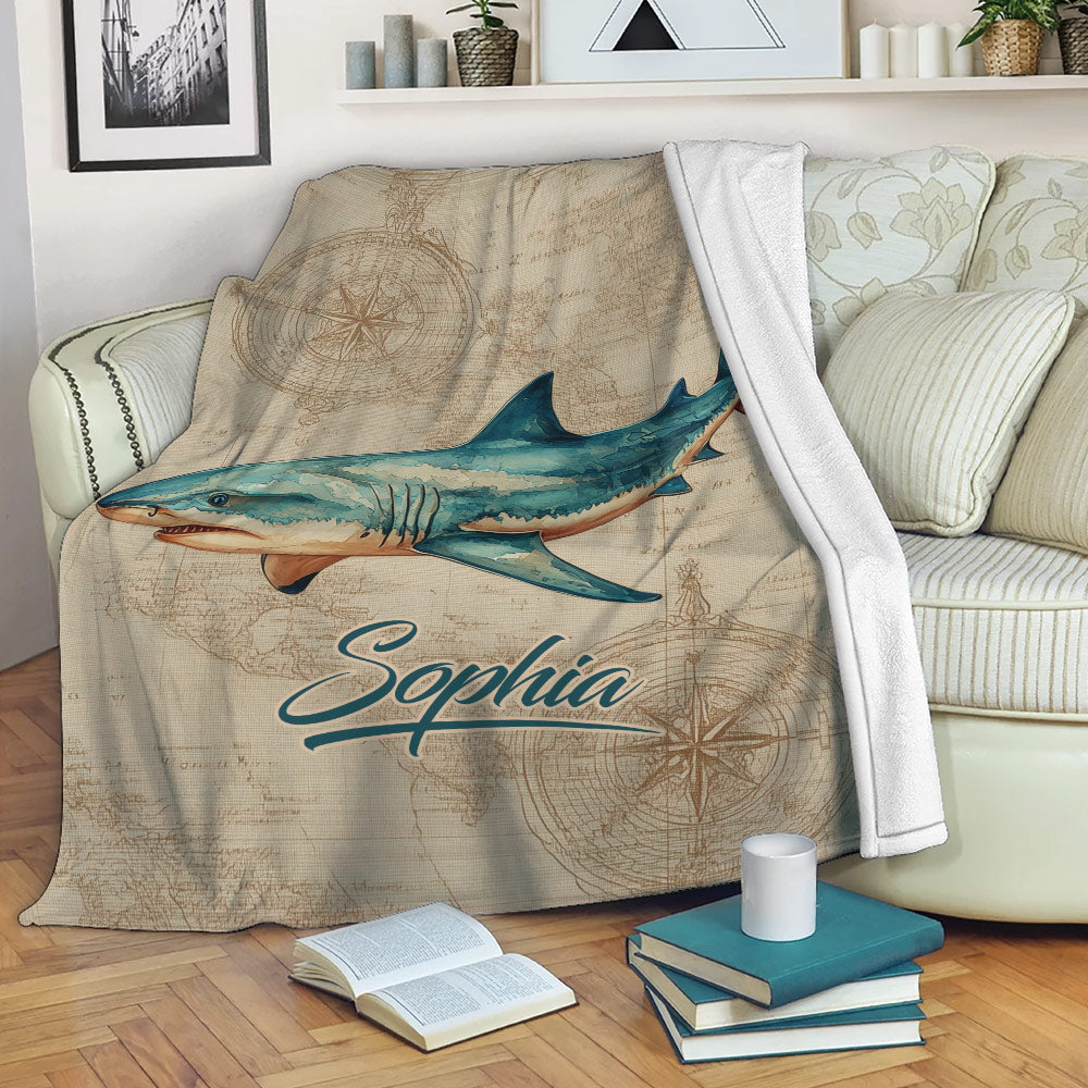 Shark blanket draped over a sofa with vintage nautical map and compass artwork