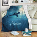 Shark blanket draped over a sofa, featuring an underwater hammerhead shark design in rich blue tones
