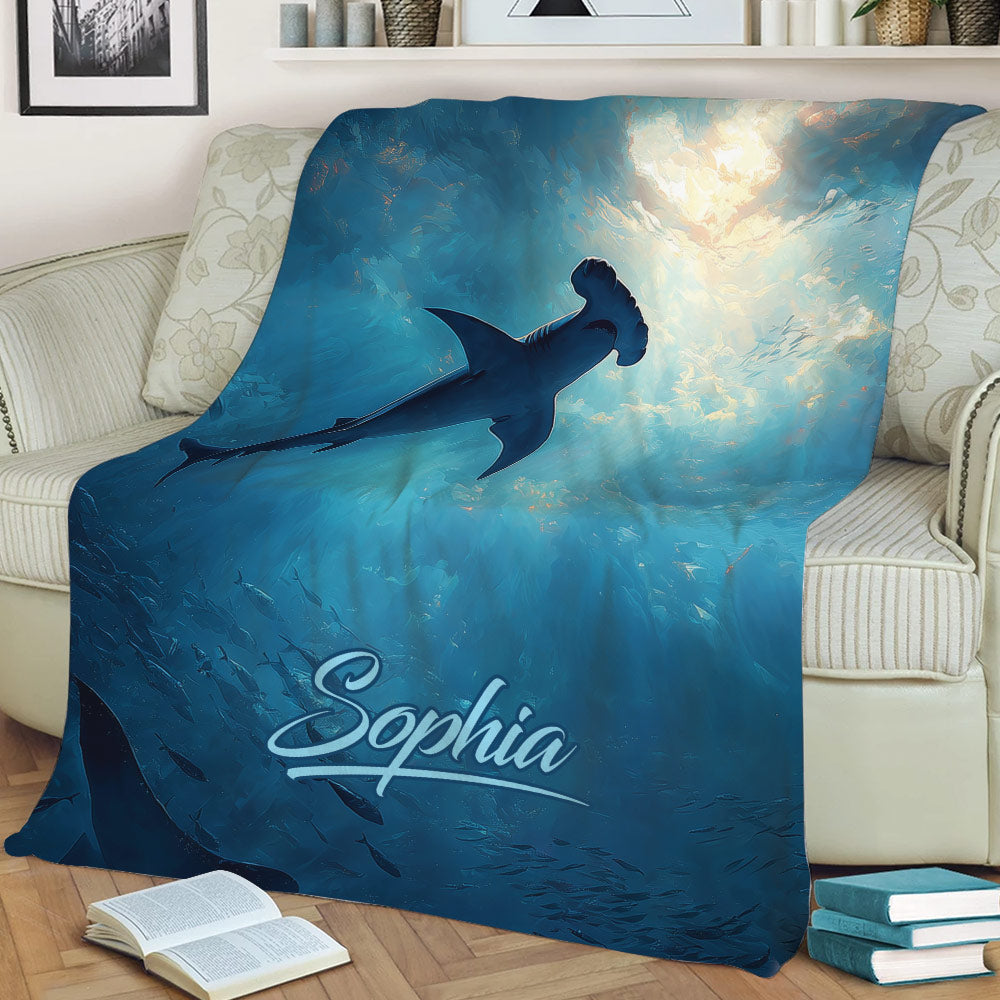 Blue shark throw blanket styled on a sofa with underwater artwork, swimming fish and ocean light