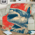 Close view of a shark throw blanket covering a couch with illustrated waves and vintage colors