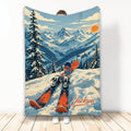 Skiing blanket with orange skis, snowy alpine mountains, evergreen trees, and sunset artwork