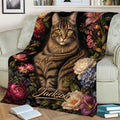 Tabby cat blanket featuring botanical flowers, styled over an armchair with books nearby
